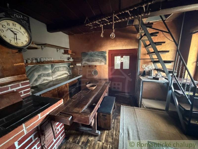 Rustic kitchen in a family house with wooden decor, ladder staircase, and brick motif.