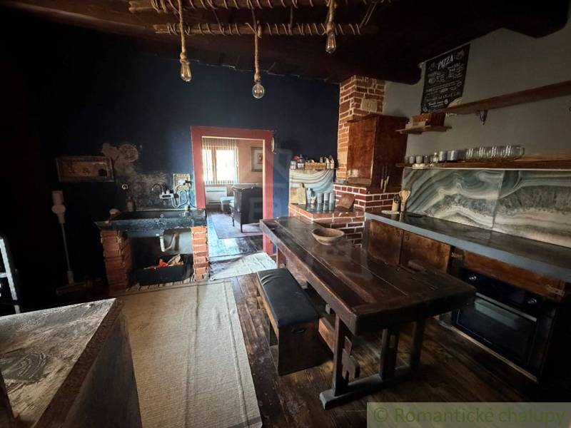 A kitchen in a family house with an antique interior, a wooden table, and a brick stove.