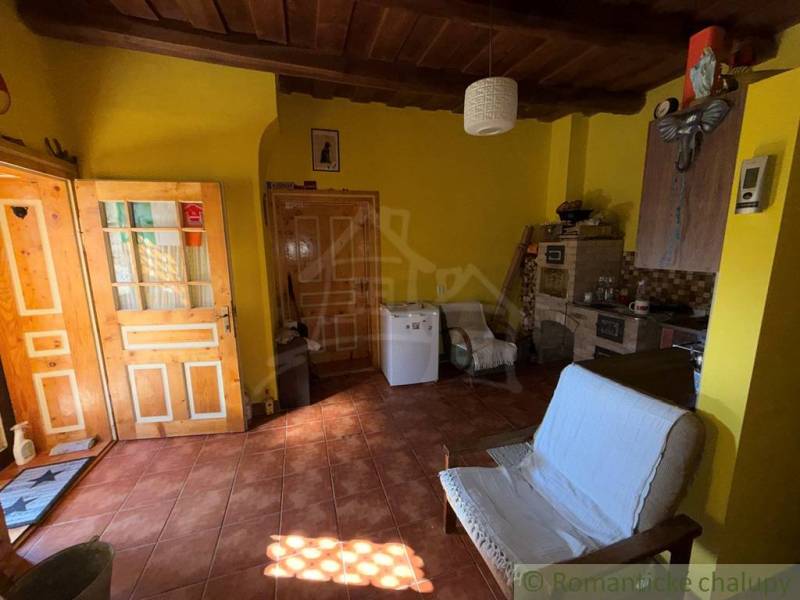 A room in a family house with a brick floor, wooden ceiling, and yellow walls.