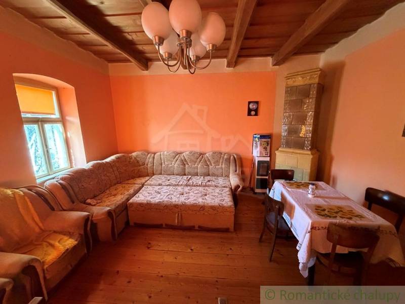 Living room with a corner sofa, wooden decor flooring, and a tiled stove in a family house.