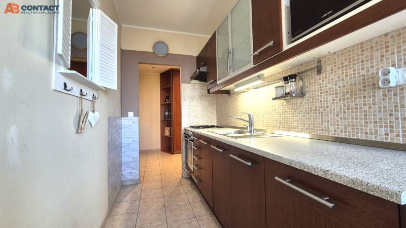 A kitchen with tiles and a countertop in a 2-room apartment, equipped with a gas stove.