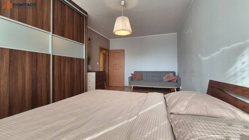 Bedroom in a 2-room apartment with a sofa, wardrobe, and wooden decor flooring.