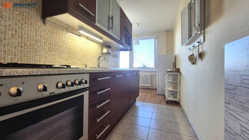 Kitchen in a 2-room apartment with a stove, wooden decor, light decoration, window with radiator.