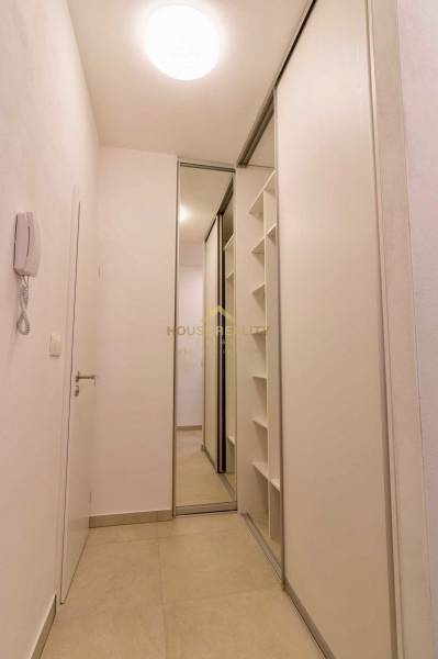 A narrow hallway in a one-room apartment with a large mirrored built-in wardrobe.
