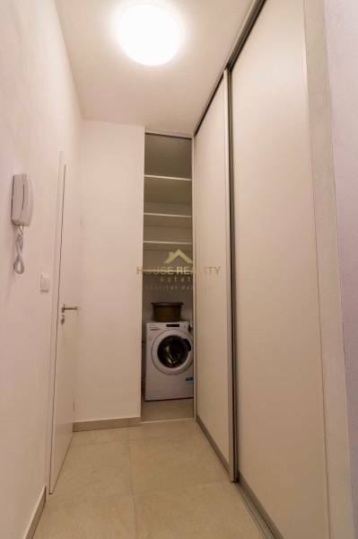 A narrow hallway in a one-room apartment with a washing machine and sliding doors.