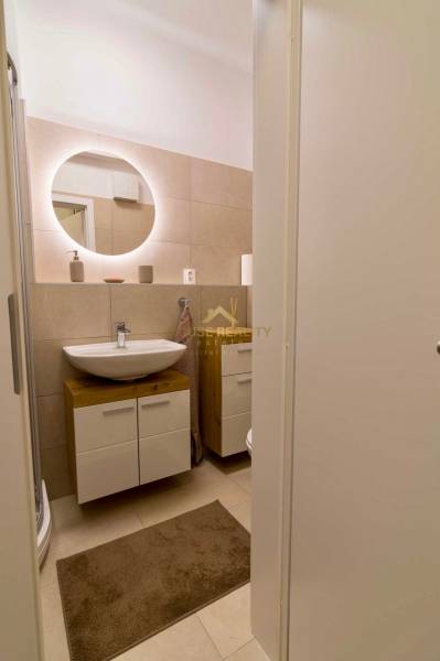 Bathroom with a sink and a mirror, part of a studio apartment.