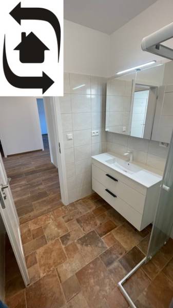A bathroom in a family house with a wooden decor floor and a shower corner.