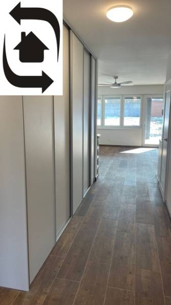 A hallway in a family house with a wooden decor floor, large windows, built-in wardrobes.