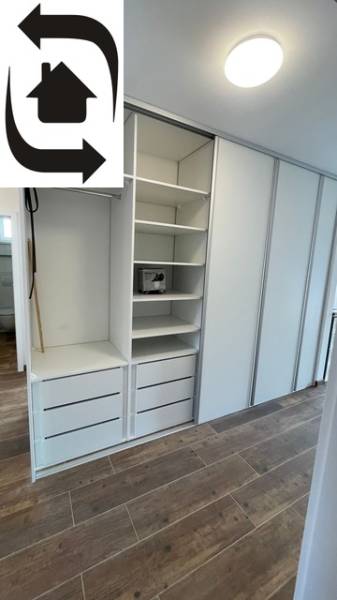 White built-in wardrobe with shelves and drawers in a family house, floor with wooden decor.