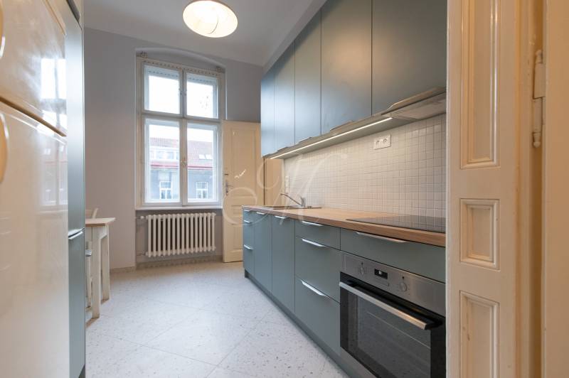 A kitchen with white tiles in a 3-room apartment, equipped with a modern kitchen unit and a stove.
