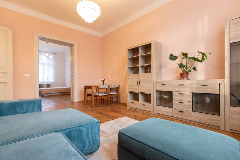 Living room in a three-room apartment with a wooden decor floor and pastel walls.