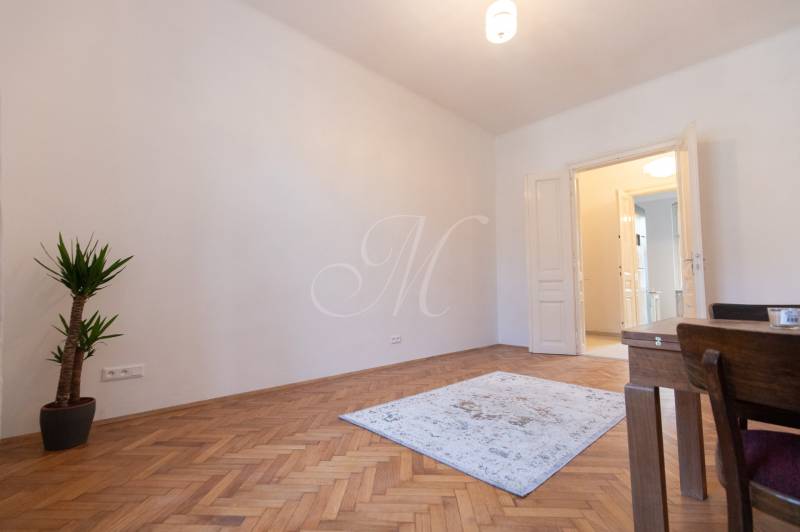 A room in a 3-room apartment with a wooden decor floor, a plant, a carpet.