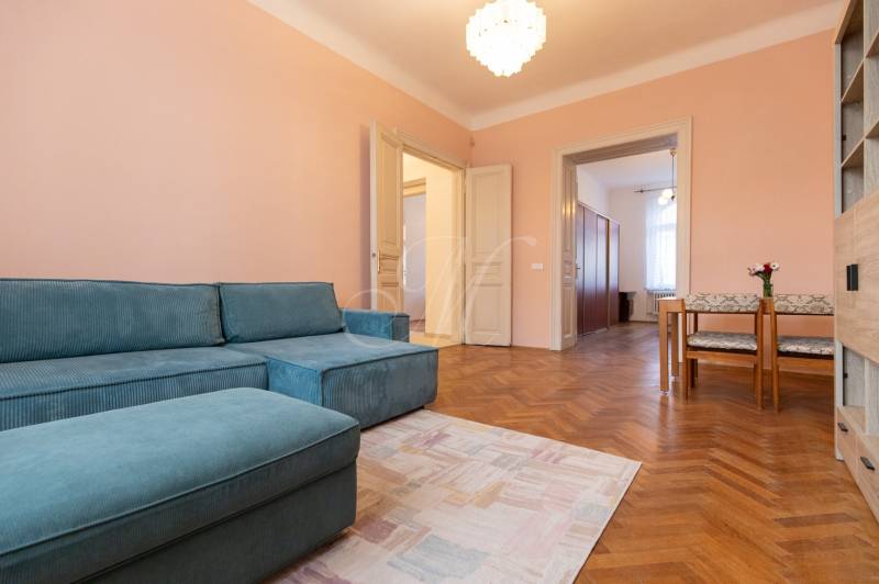 A room in a 3-room apartment with a blue sofa, wooden floor decor, and a dining area.