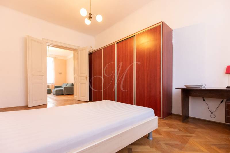 A bedroom with wood-patterned flooring, white furniture, and a spacious wardrobe.