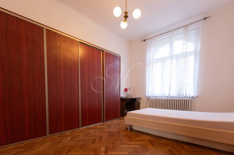 Bedroom with a bed, wooden decor flooring, large wardrobe in a 3-room apartment.
