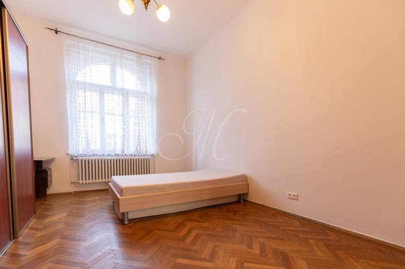 A bright room with a bed and a wooden decor floor in a 3-room apartment.