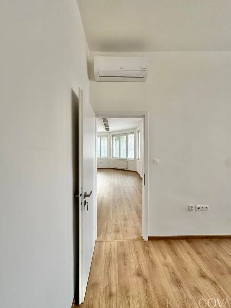 The doors lead to an office with a wooden decor floor and air conditioning.