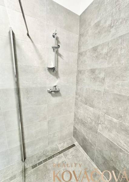 A shower corner with modern tiles and stainless steel accessories in the office.