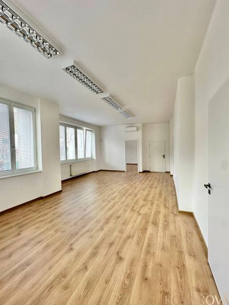 Offices with wood-patterned flooring, white walls, and windows offer a bright working space.