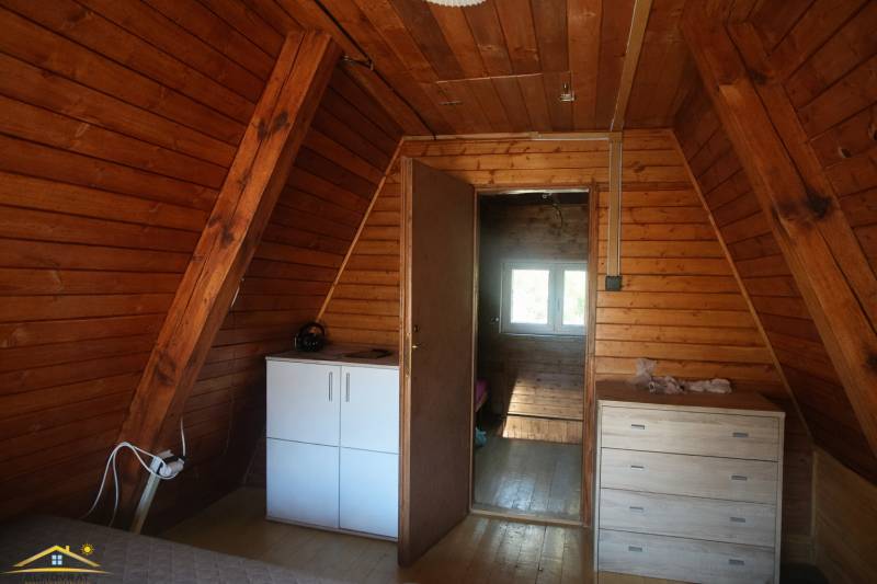 Interior of a cabin with wooden walls, a dresser, and a floor with a wooden decor.