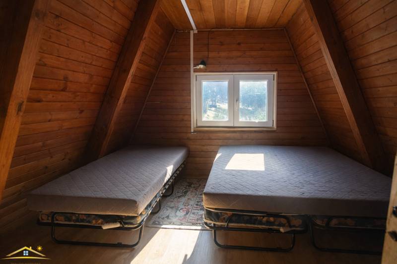 Attic room in a cottage with two beds and a wooden decor floor.