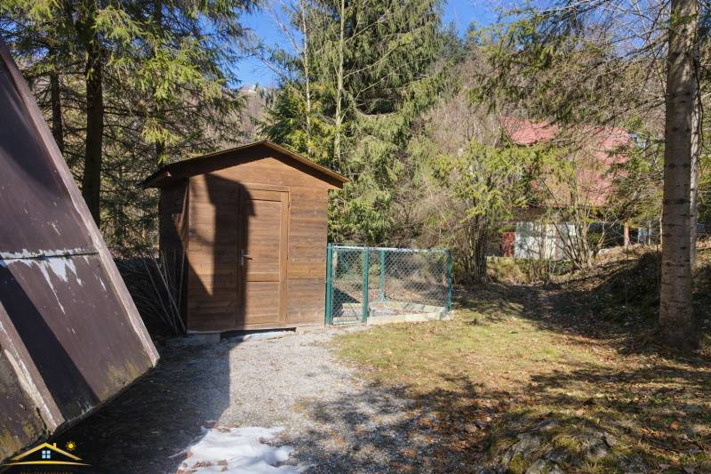 A wooden shelter and fence in a natural setting near a cottage in Oščadnica.