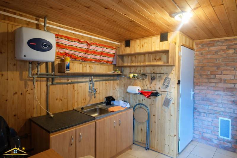 Interior of a cabin with wooden decor, kitchen unit, and brick cladding.