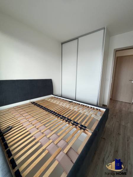 A bedroom in a 3-room apartment with a bed frame and a built-in wardrobe.