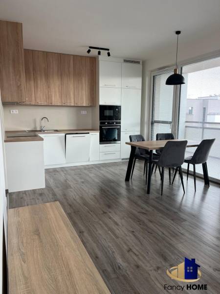 A kitchen with built-in appliances and a dining table in a 3-room apartment, floor with a wooden decor.