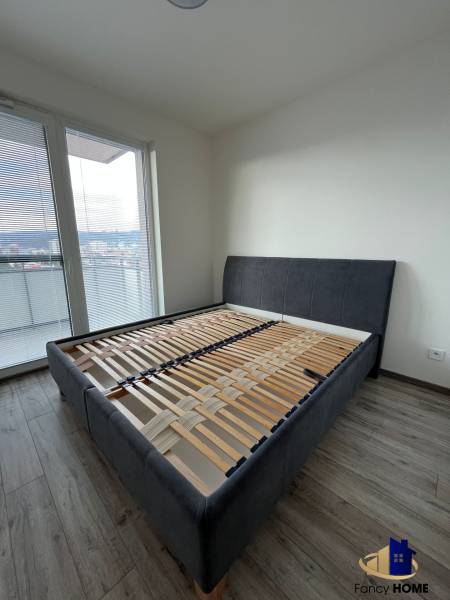 In the 3-room apartment, there is a bed with gray upholstery and a floor with a wooden decor.