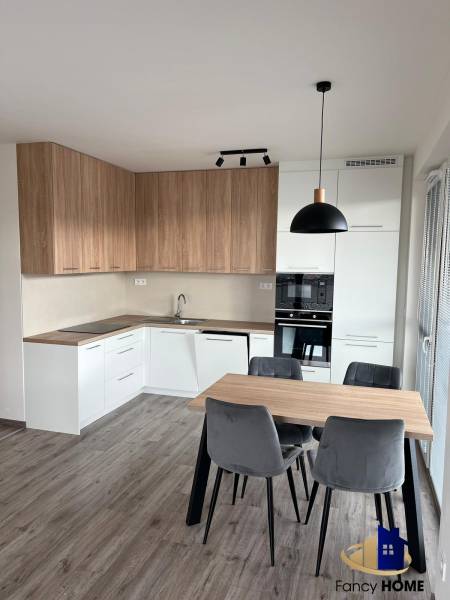 A kitchen in a 3-room apartment with a corner kitchen unit and a wooden decor floor.