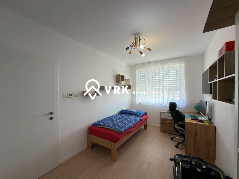 Children's room in a three-room apartment with a wooden decor floor, a desk, a bed.