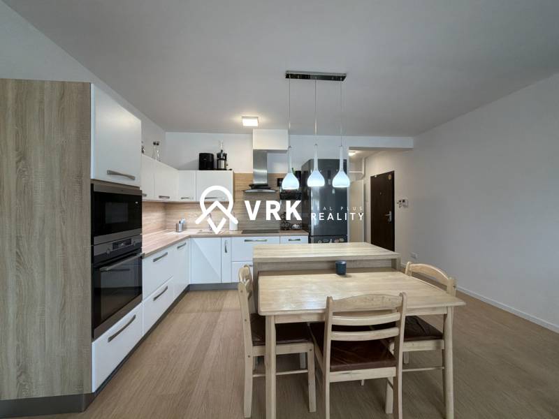 A kitchen in a 3-room apartment with a wooden decor floor and a dining table.