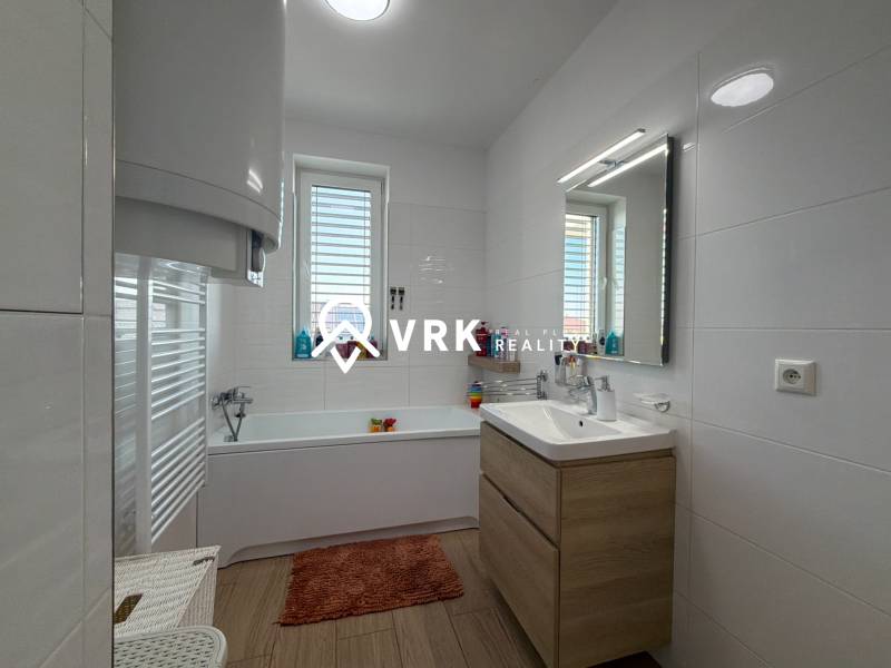 Bathroom with a bathtub and a sink in a 3-room apartment, white tiles, floor with wood decor.