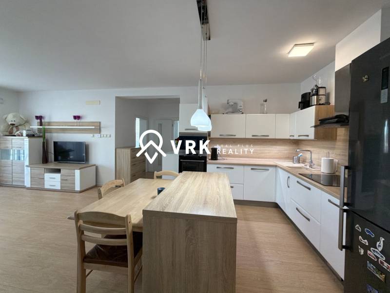 A kitchen in a 3-room apartment, a floor with a wooden decor, modern appliances, and a dining table.