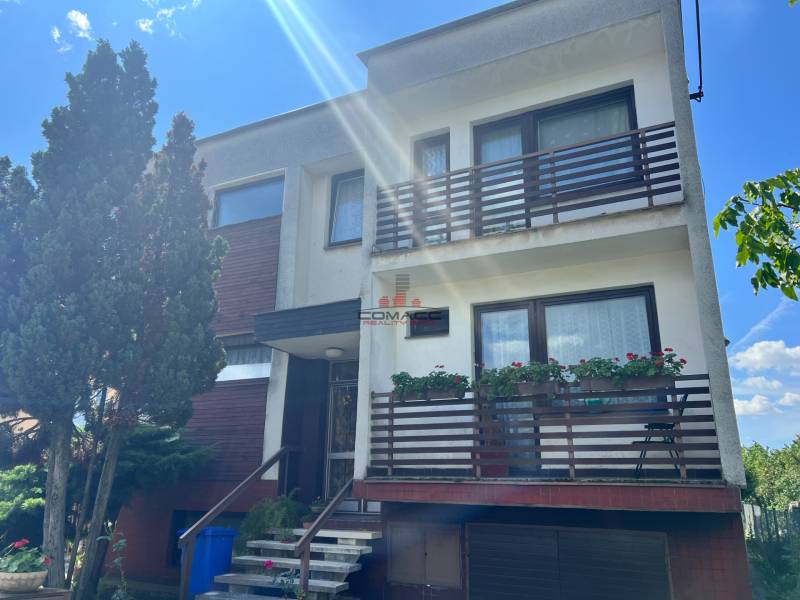 A family house on Tálová Street in Veľké Orvište with two balconies, trees, and a garage.