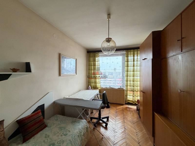 A room in a family house with a wooden decor floor, a couch, and a large wardrobe.