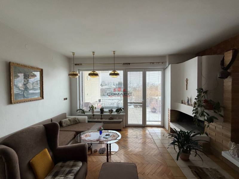 Living room in a family house with a fireplace, sofa, and wooden decor flooring.