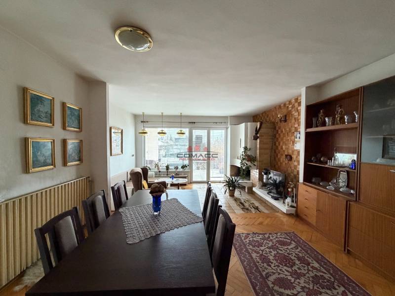 Living room in a family house with a wood-patterned floor, dining table, and fireplace.