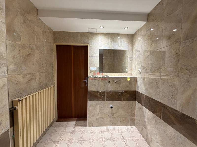 A bathroom in a family house with tiles, a mirror, and a radiator.
