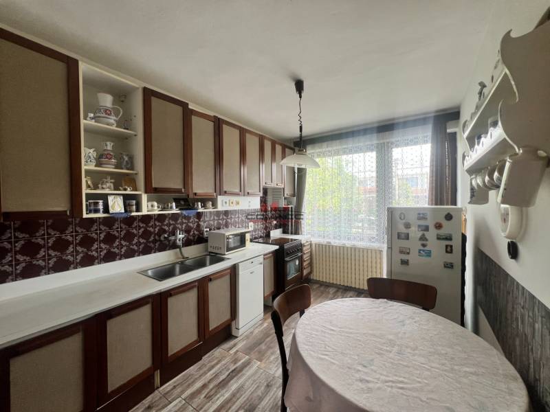 A kitchen in a family house with wooden cabinets, a round table, and a floor with a wooden decor.