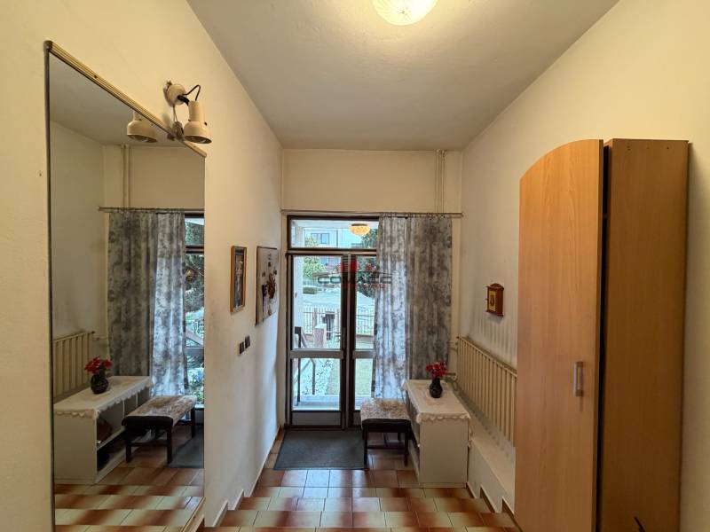 Interior of a family house with a mirror, wardrobe, tiles, and a view of the garden.