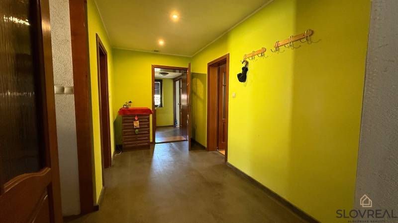 A hallway with coat racks and yellow walls, a floor with a wooden decor in a family house.