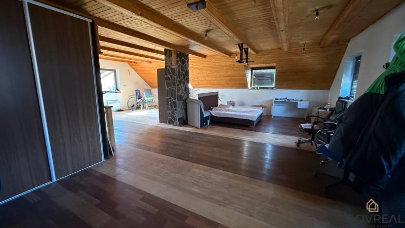 Attic room with a bed, wardrobe, and wooden decor flooring in a family house.