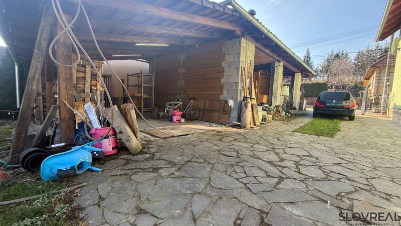 A family house in Lutila with a wooden shelter, a stone courtyard, and a parked car.