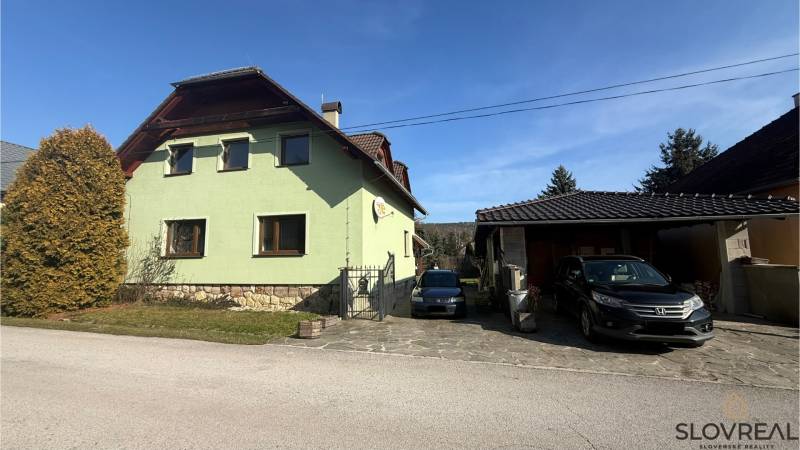 A family house in Lutila with two cars parked in front of the garage on a paved driveway.