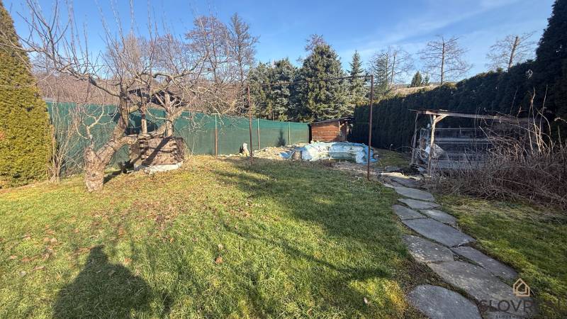 The garden of a family house in Lutila with trees and a pathway in a sunny environment.