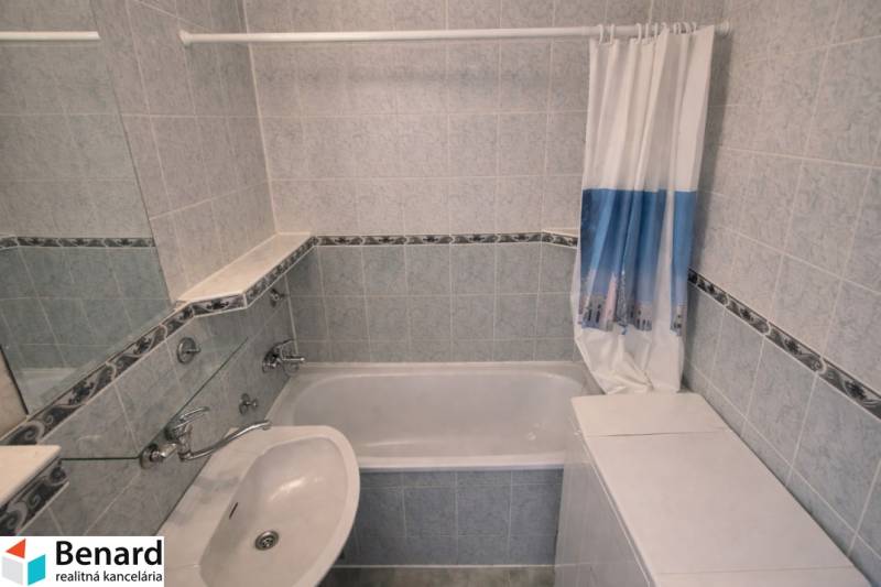 Bathroom with a bathtub and a sink in a 2-room apartment, tiled walls.
