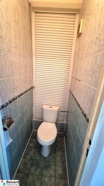 Small bathroom with a toilet and tiles in a 2-room apartment, roller blind on the window.