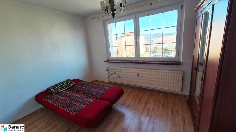 A bedroom with a bed, wardrobe, and wooden decor flooring in a two-room apartment.